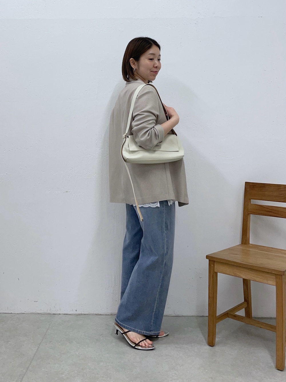 ホワイト系のショルダーバッグ、ベージュ系のテーラードジャケット、ホワイト系のキャミソールを着用したレディースの春コーディネートの4枚目の写真
