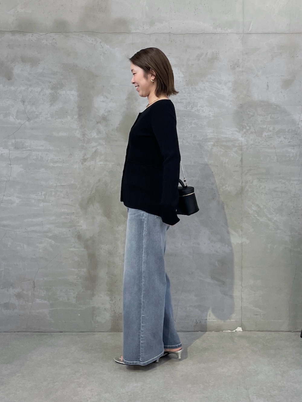 ブラック系のカーディガン/ボレロ、ブルー系のデニムパンツ、ブラック系のショルダーバッグを着用したレディースの春コーディネートの2枚目の写真