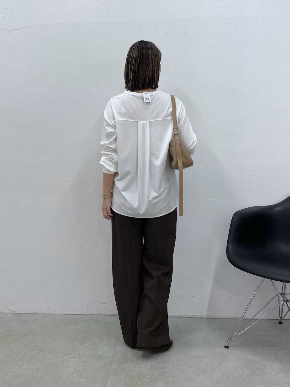 ホワイト系のTシャツ/カットソー、ブラウン系のスラックス、ベージュ系のショルダーバッグを着用したレディースの夏コーディネートの3枚目の写真