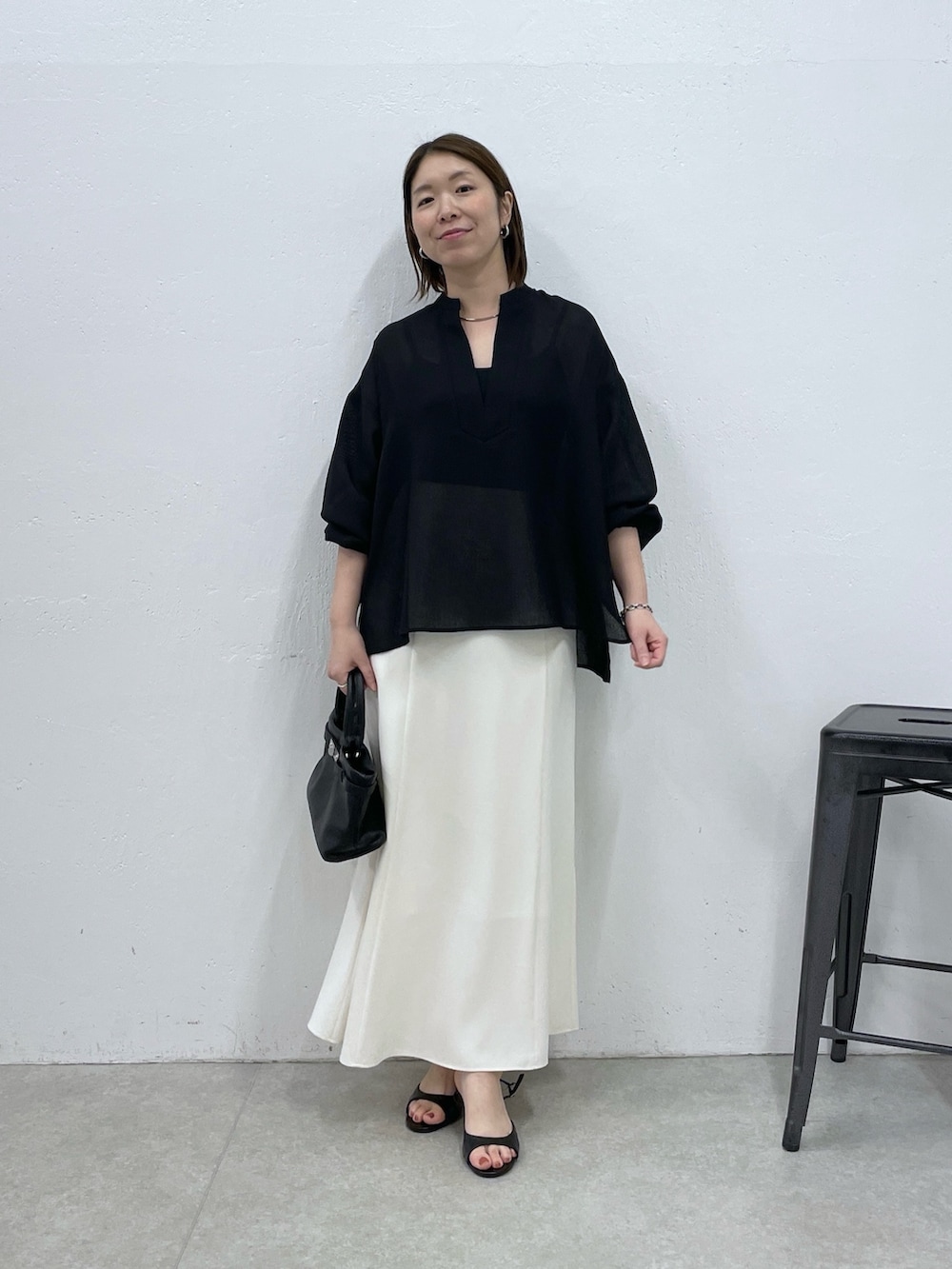 ホワイト系のスカート、ブラック系のトートバッグ、ブラック系のシャツ/ブラウスを着用したレディースの春コーディネートの4枚目の写真