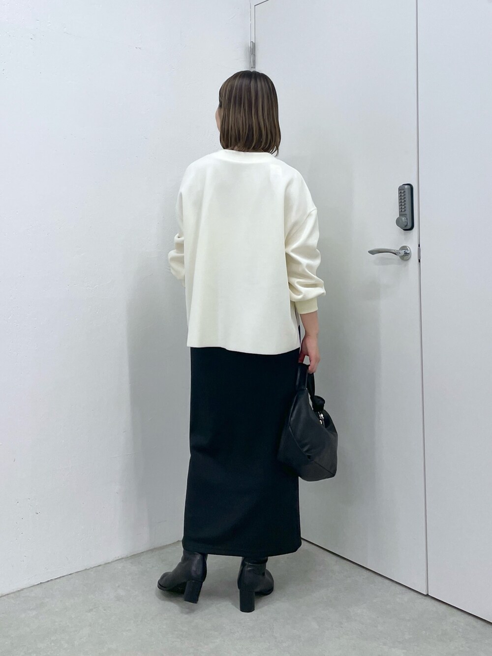 ホワイト系のカーディガン/ボレロ、ブラック系のスカート、ブラック系のショルダーバッグを着用したレディースの秋コーディネートの2枚目の写真