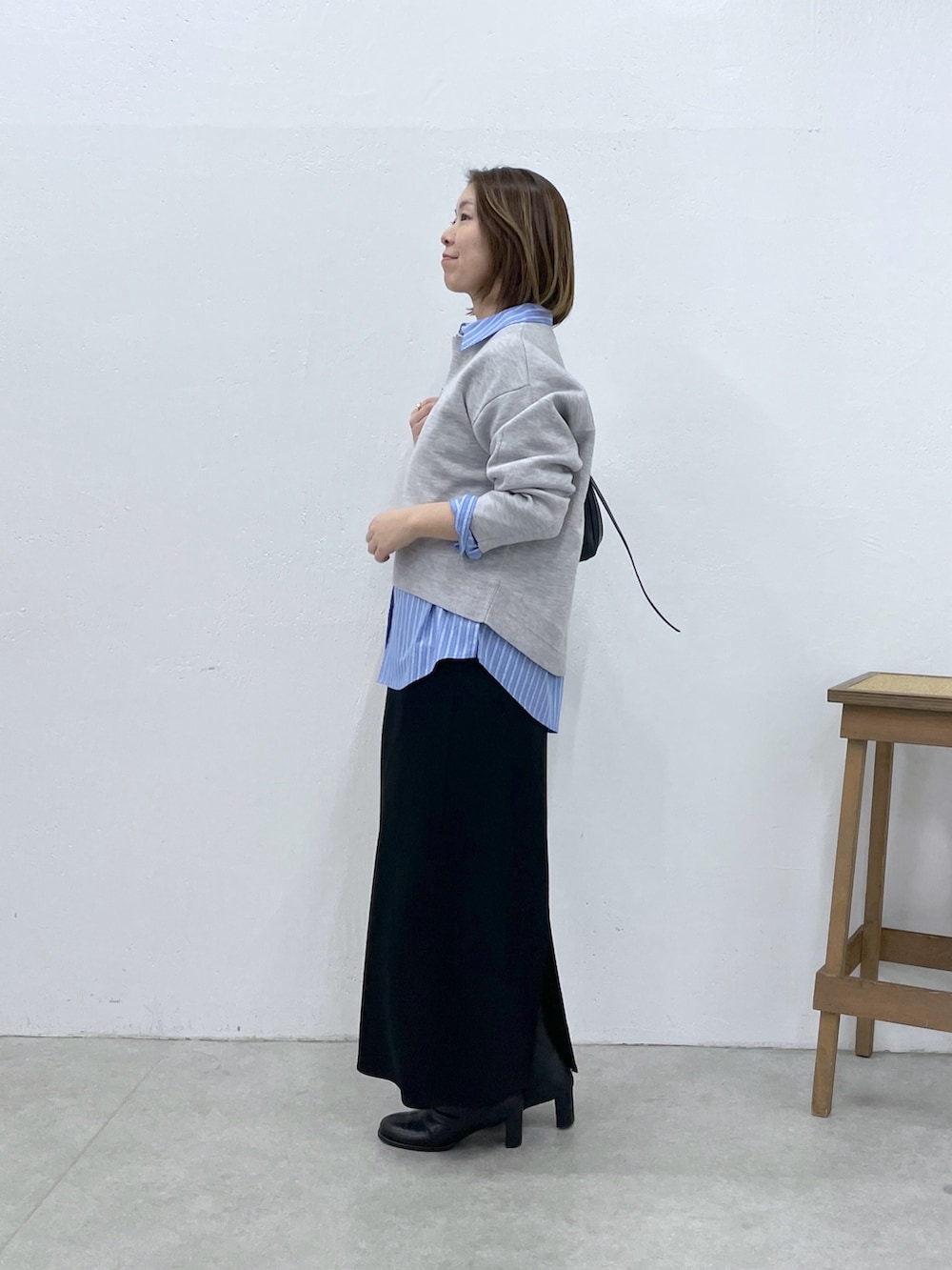 グレー系のニット/セーター、ブラック系のスカート、ブルー系のシャツ/ブラウスを着用したレディースの冬コーディネートの2枚目の写真
