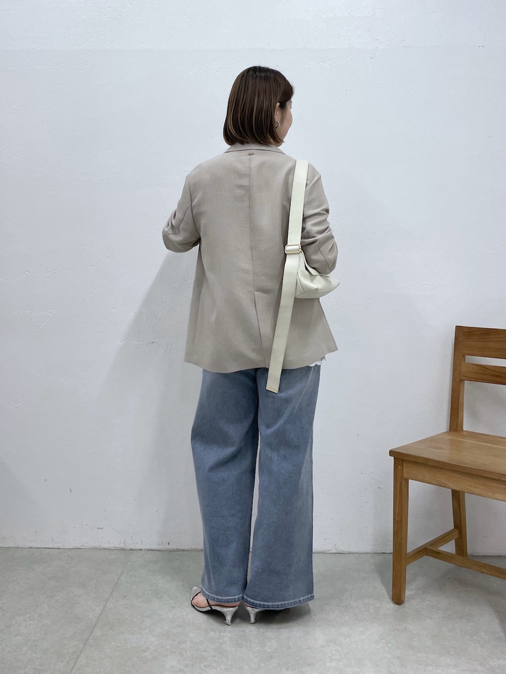 ホワイト系のショルダーバッグ、ベージュ系のテーラードジャケット、ホワイト系のキャミソールを着用したレディースの春コーディネートの3枚目の写真