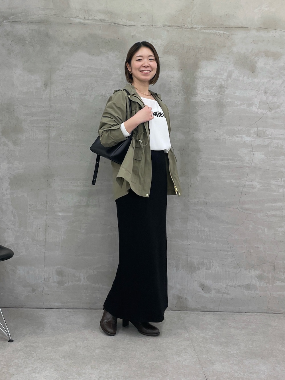 ホワイト系のTシャツ/カットソー、グリーン系のブルゾン、ブラック系のスカートを着用したレディースの冬コーディネートの2枚目の写真