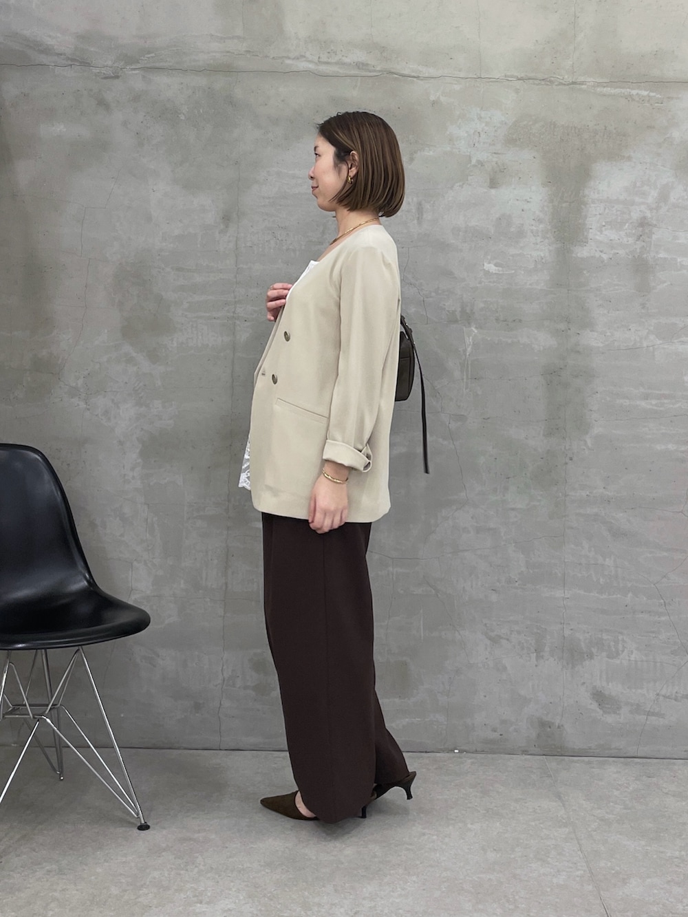 ベージュ系のノーカラージャケット、ホワイト系のキャミソール、ブラウン系のスラックスを着用したレディースの冬コーディネートの2枚目の写真