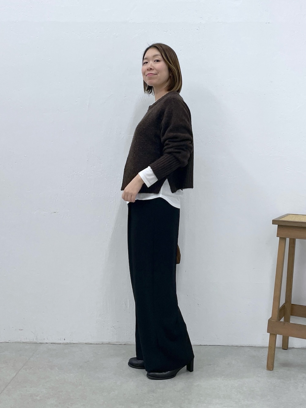 ホワイト系のTシャツ/カットソー、ブラウン系のニット/セーター、ブラック系のスラックスを着用したレディースの冬コーディネートの2枚目の写真
