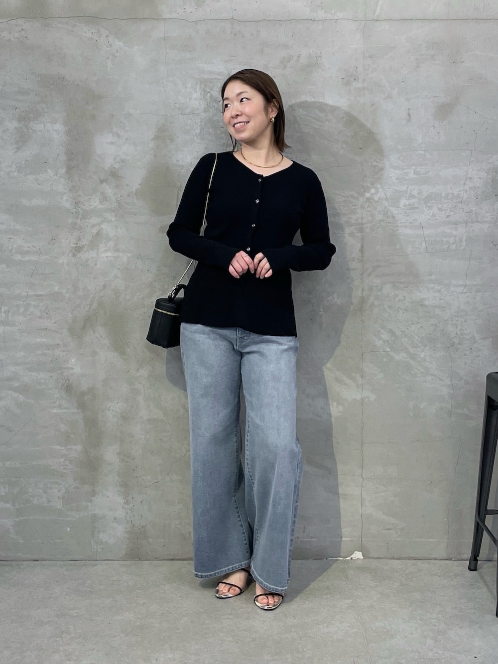 ブラック系のカーディガン/ボレロ、ブルー系のデニムパンツ、ブラック系のショルダーバッグを着用したレディースの春コーディネートの5枚目の写真