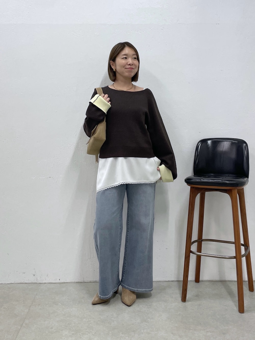 ブラウン系のニット/セーター、ホワイト系のキャミソール、ブルー系のデニムパンツを着用したレディースの秋コーディネートの4枚目の写真