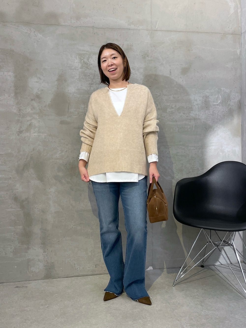 ベージュ系のニット/セーター、ブルー系のデニムパンツ、ブラウン系のバッグを着用したレディースの秋コーディネートの4枚目の写真