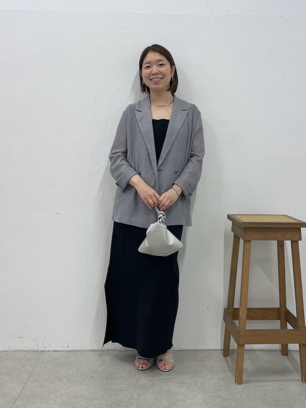 ブラック系のワンピース、グレー系のテーラードジャケット、シルバー系のネックレスを着用したレディースの春コーディネートの4枚目の写真