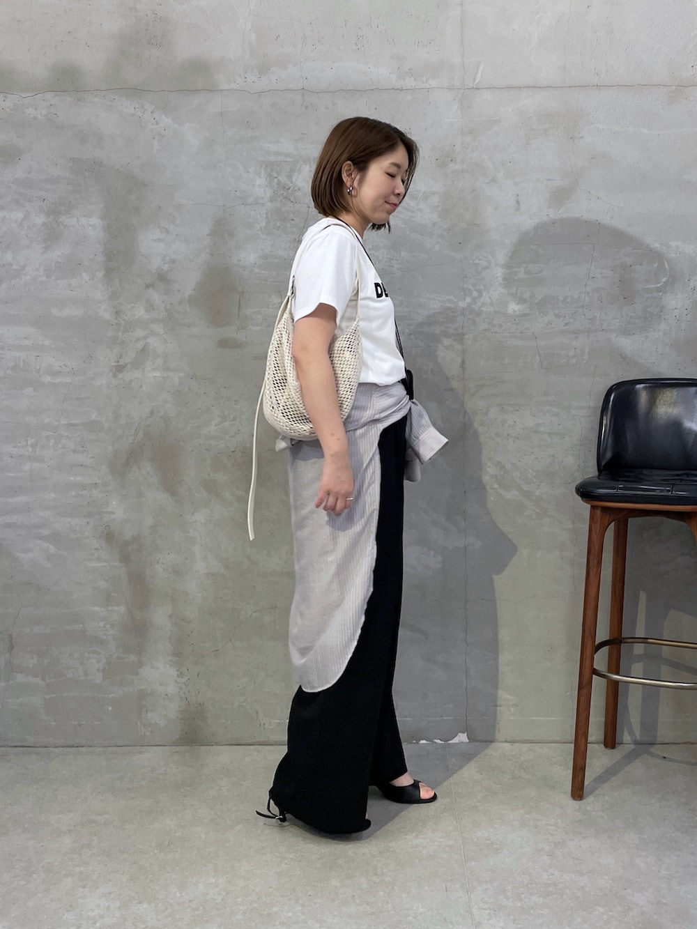 ブラック系のスラックス、ホワイト系のショルダーバッグ、ホワイト系のTシャツ/カットソーを着用したレディースの夏コーディネートの4枚目の写真