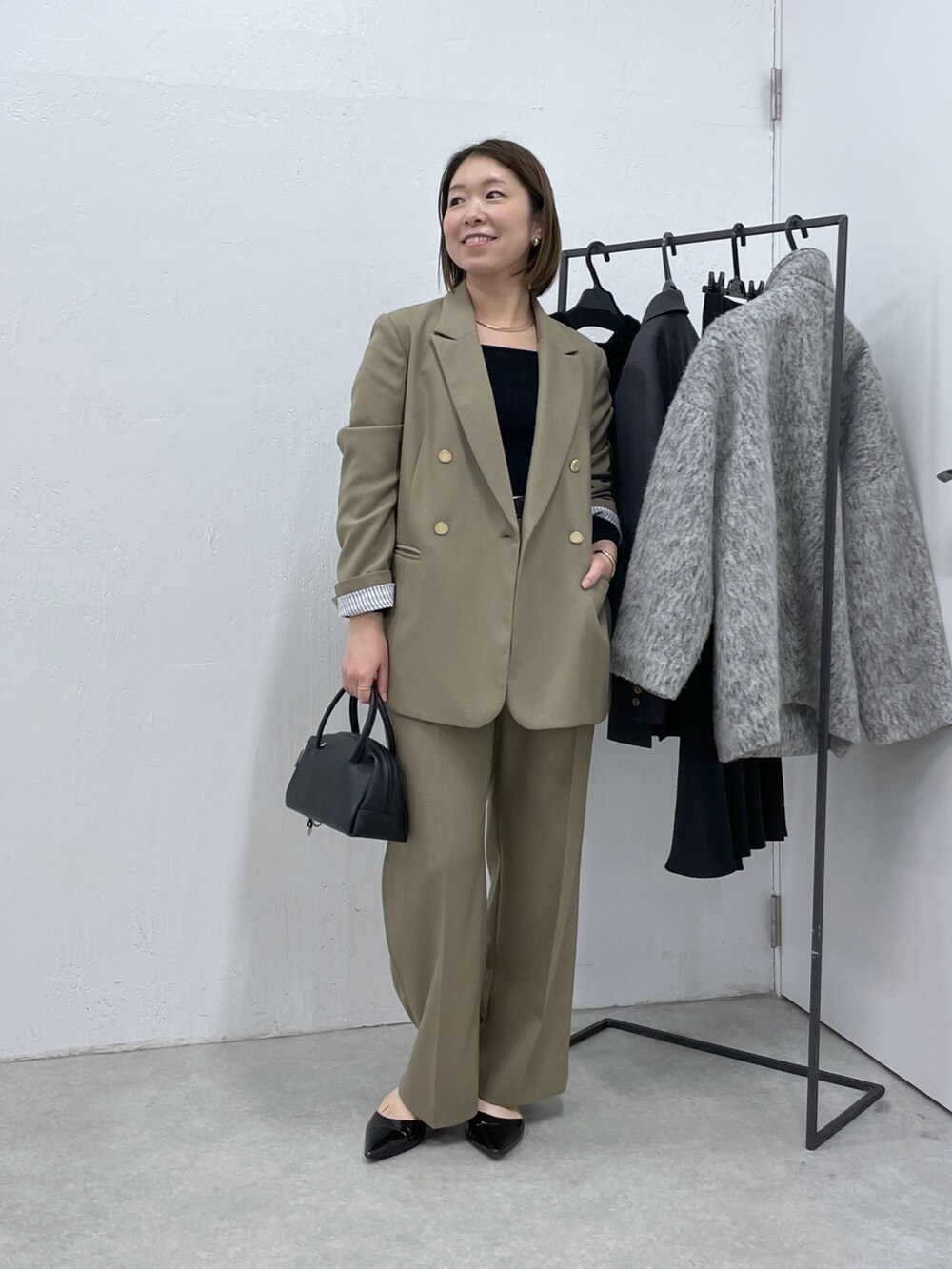 ベージュ系のスラックス、ブラック系のニット/セーター、ベージュ系のテーラードジャケットを着用したレディースの冬コーディネートの4枚目の写真