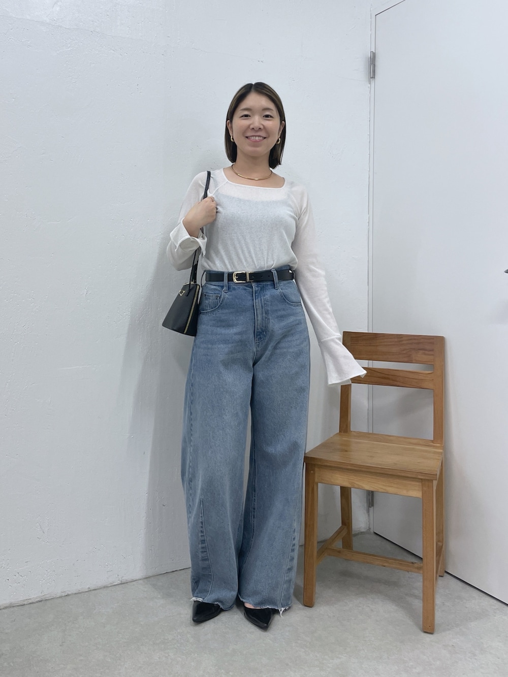 ホワイト系のTシャツ/カットソー、ブルー系のデニムパンツ、ブラック系のベルトを着用したレディースの秋コーディネートの4枚目の写真