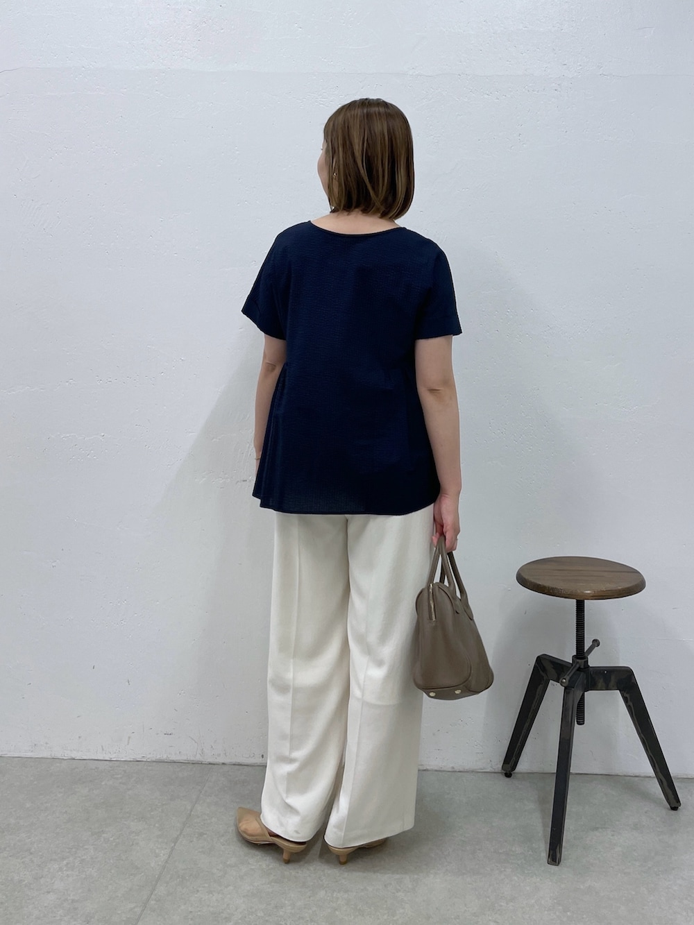 ブルー系のシャツ/ブラウス、ホワイト系のスラックス、ブラウン系のボストンバッグを着用したレディースの春コーディネートの3枚目の写真