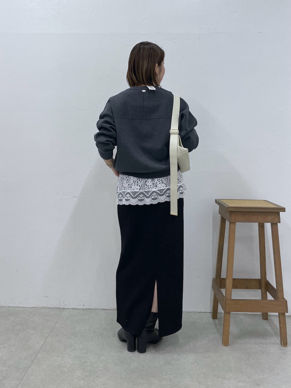 グレー系のニット/セーター、ホワイト系のキャミソール、ブラック系のスカートを着用したレディースの冬コーディネートの3枚目の写真