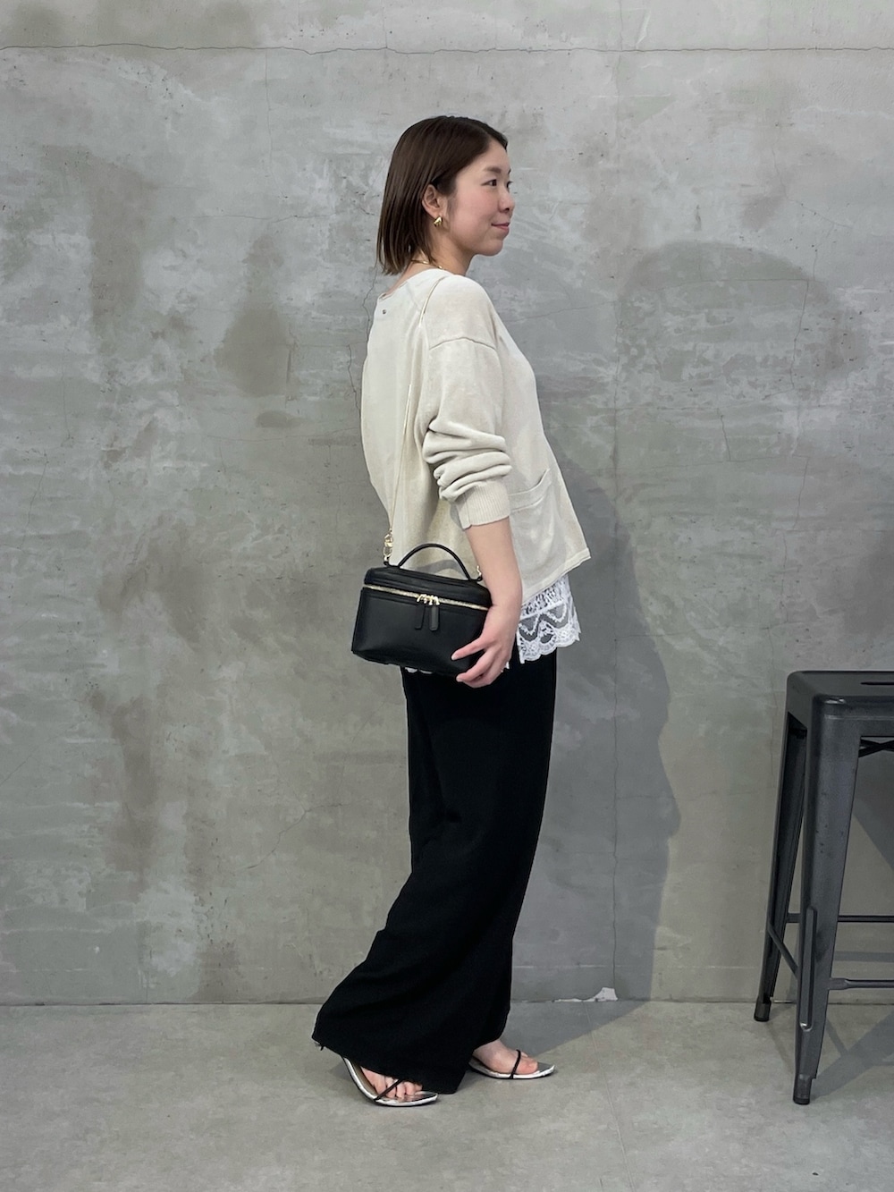 ベージュ系のカーディガン/ボレロ、ホワイト系のキャミソール、ブラック系のスラックスを着用したレディースの春コーディネートの2枚目の写真