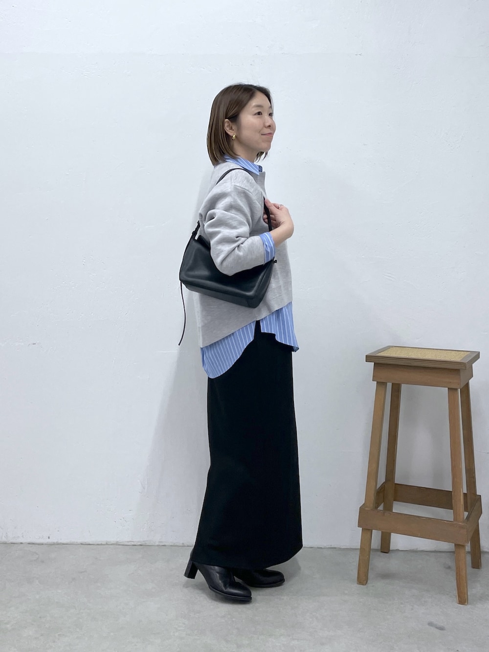 グレー系のニット/セーター、ブラック系のスカート、ブルー系のシャツ/ブラウスを着用したレディースの冬コーディネートの4枚目の写真