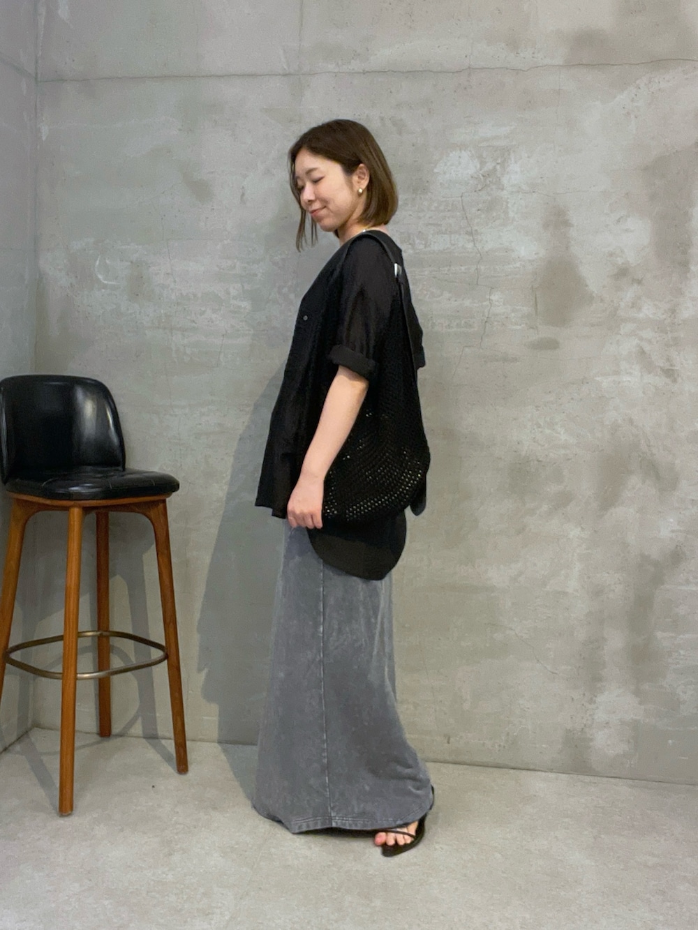 ブラック系のシャツ/ブラウス、グレー系のスカート、ブラック系のショルダーバッグを着用したレディースの夏コーディネートの2枚目の写真