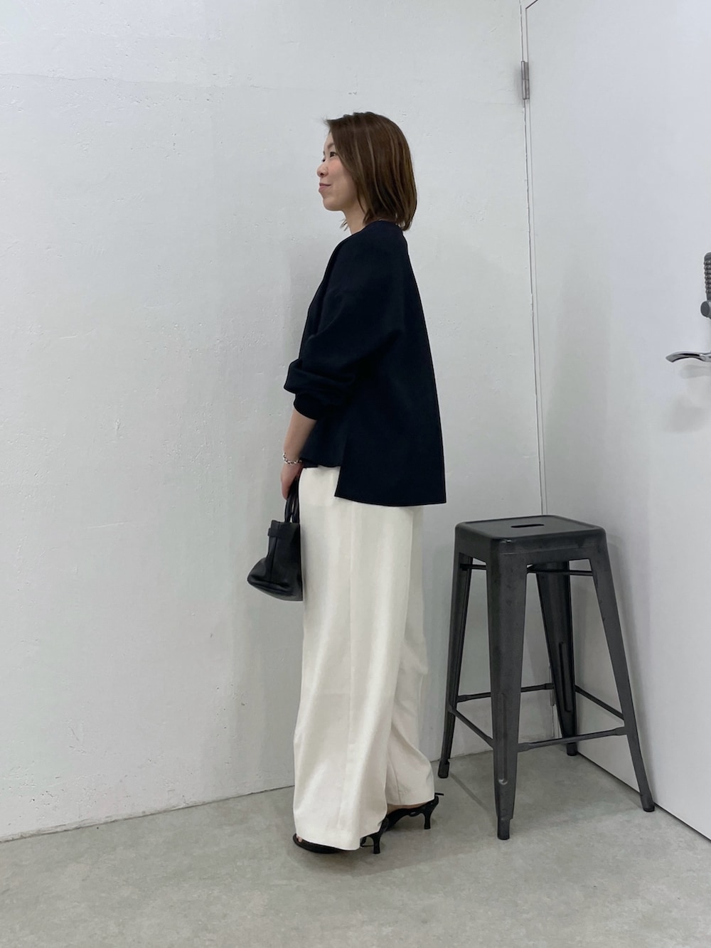 ブルー系のカーディガン/ボレロ、ホワイト系のスラックス、ブラック系のトートバッグを着用したレディースの春コーディネートの3枚目の写真