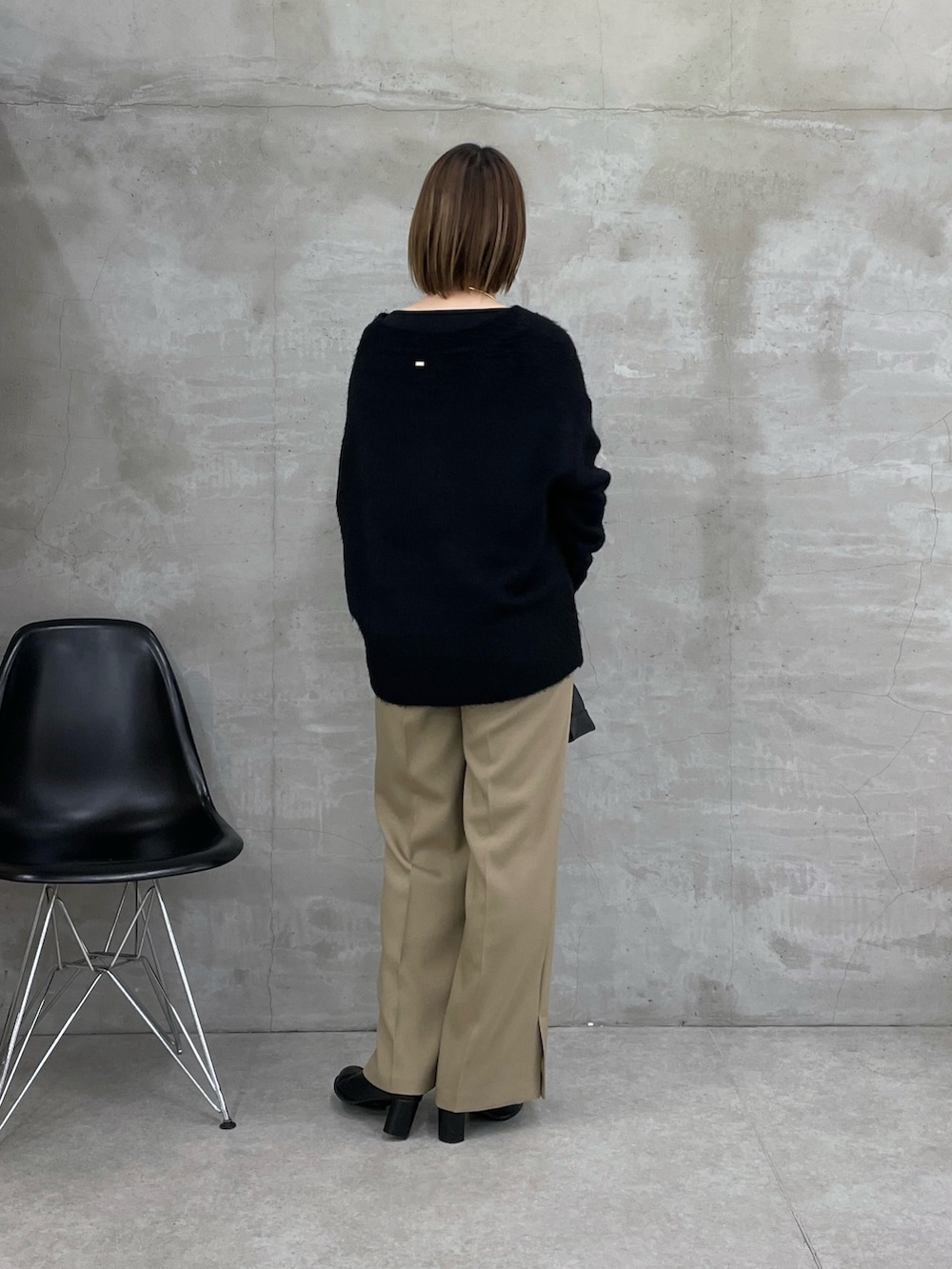 ブラック系のニット/セーター、ブラック系のTシャツ/カットソー、ベージュ系のスラックスを着用したレディースの冬コーディネートの3枚目の写真