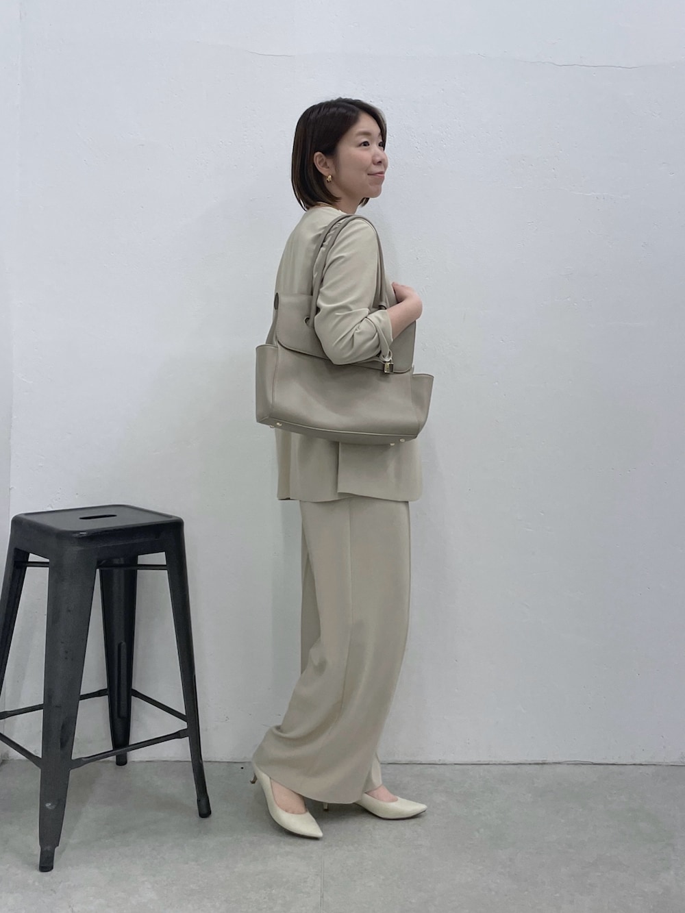 ベージュ系のスラックス、ベージュ系のノーカラージャケット、ホワイト系のキャミソールを着用したレディースの冬コーディネートの4枚目の写真