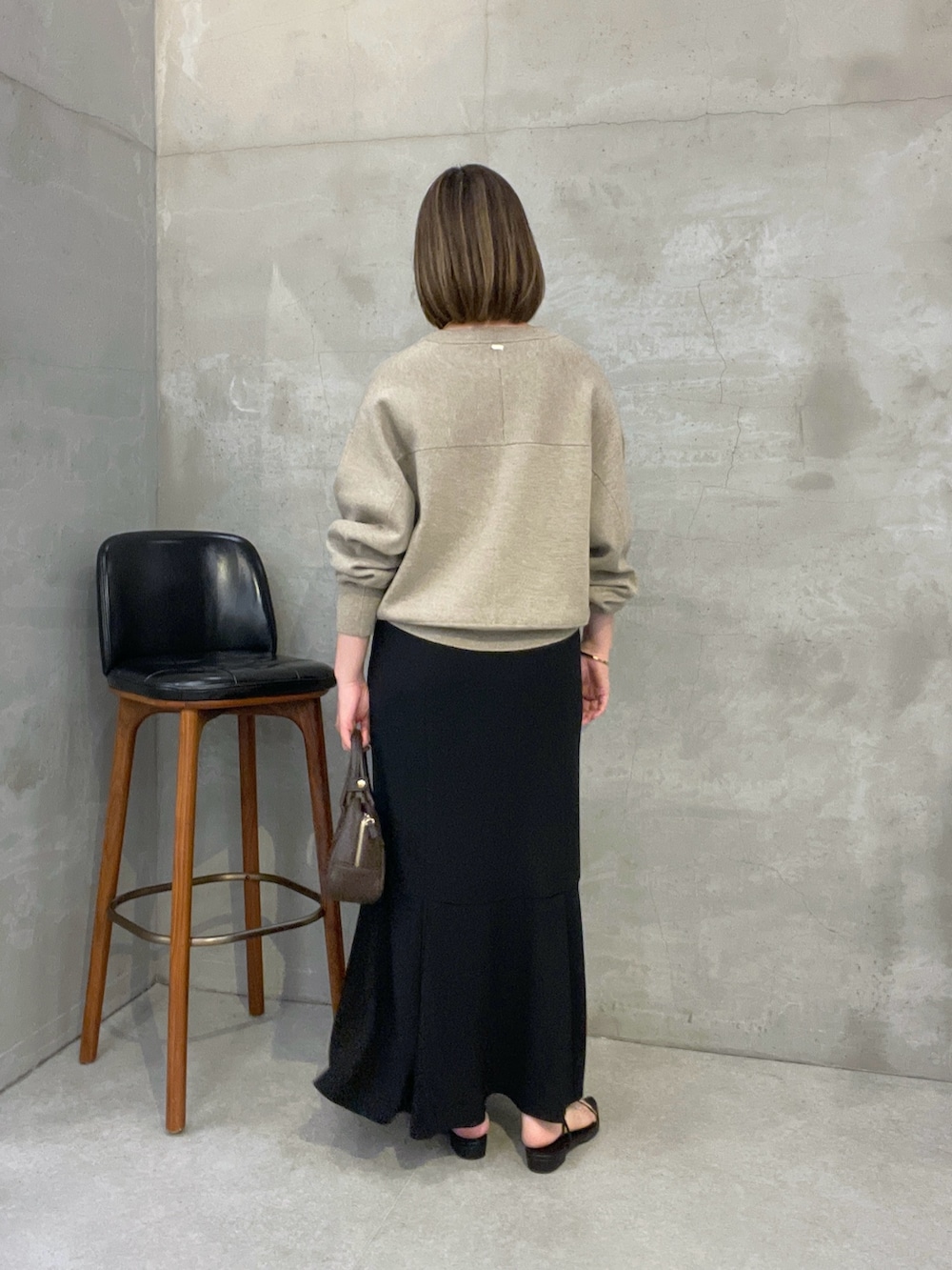 ベージュ系のニット/セーター、ブラック系のスカート、ブラウン系のショルダーバッグを着用したレディースの夏コーディネートの2枚目の写真