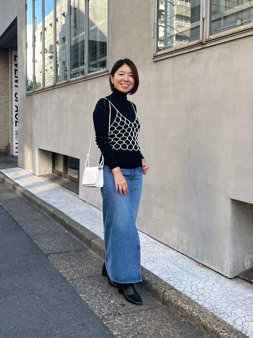 ホワイト系のキャミソール、ブルー系のデニムスカートを着用したレディースの秋コーディネートの3枚目の写真