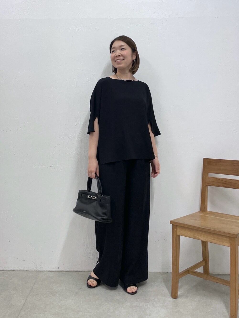 ブラック系のシャツ/ブラウス、ブラック系のスラックス、ブラック系のトートバッグを着用したレディースの春コーディネートの5枚目の写真