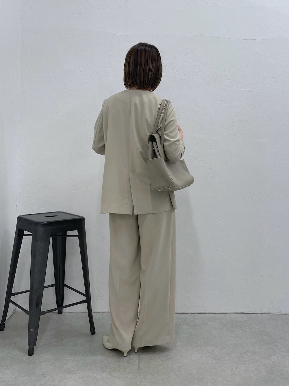 ベージュ系のスラックス、ベージュ系のノーカラージャケット、ホワイト系のキャミソールを着用したレディースの冬コーディネートの3枚目の写真