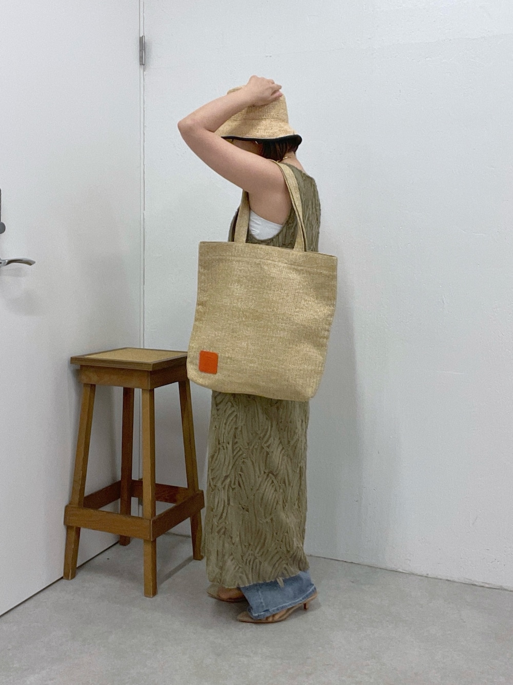 ブルー系のデニムパンツ、グリーン系のワンピース、ベージュ系のトートバッグを着用したレディースの夏コーディネートの3枚目の写真