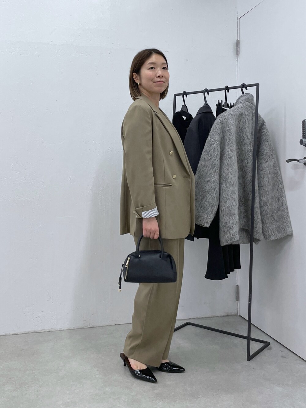 ベージュ系のスラックス、ブラック系のニット/セーター、ベージュ系のテーラードジャケットを着用したレディースの冬コーディネートの2枚目の写真