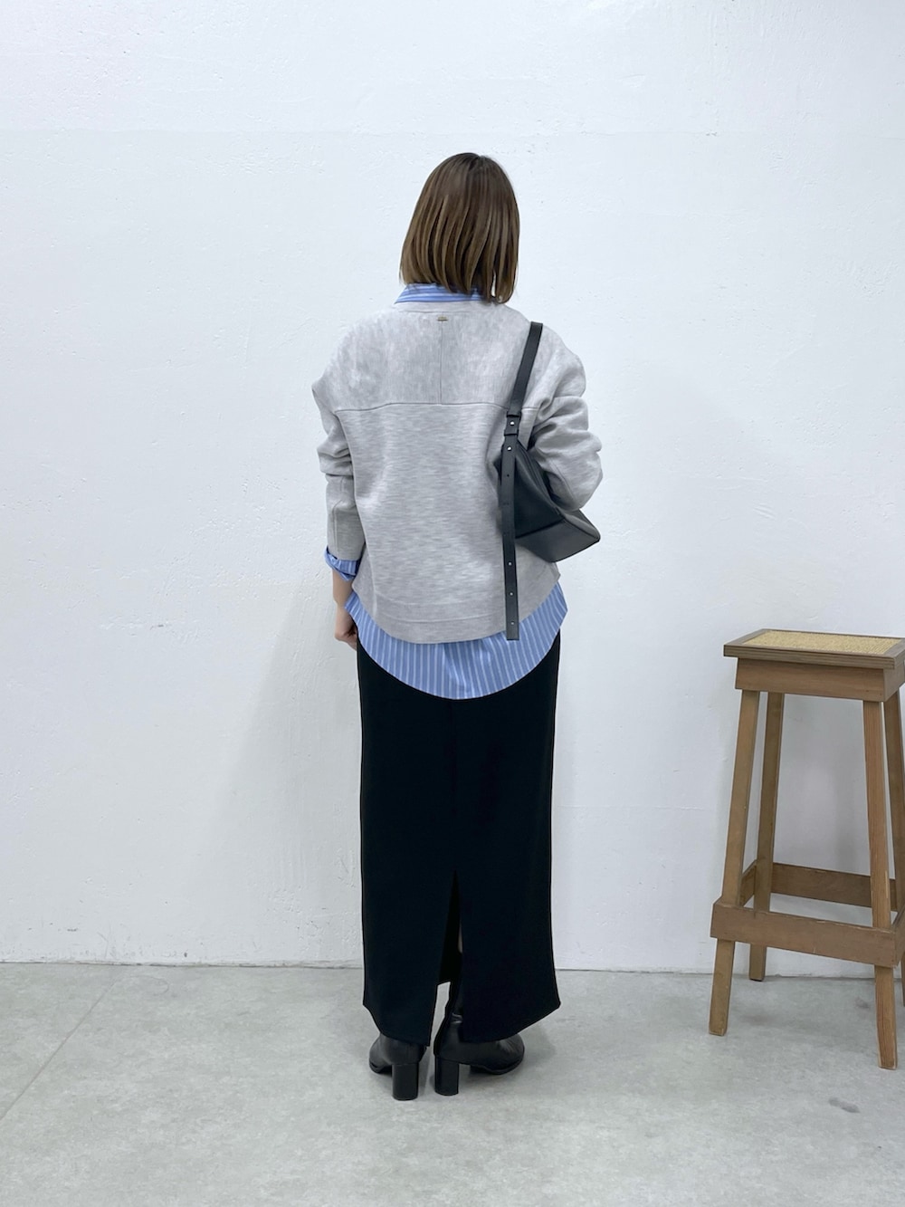 グレー系のニット/セーター、ブラック系のスカート、ブルー系のシャツ/ブラウスを着用したレディースの冬コーディネートの3枚目の写真