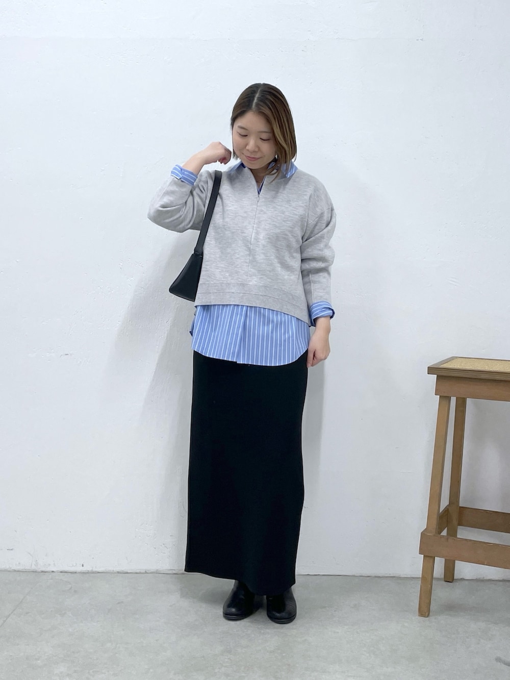 グレー系のニット/セーター、ブラック系のスカート、ブルー系のシャツ/ブラウスを着用したレディースの冬コーディネートの5枚目の写真