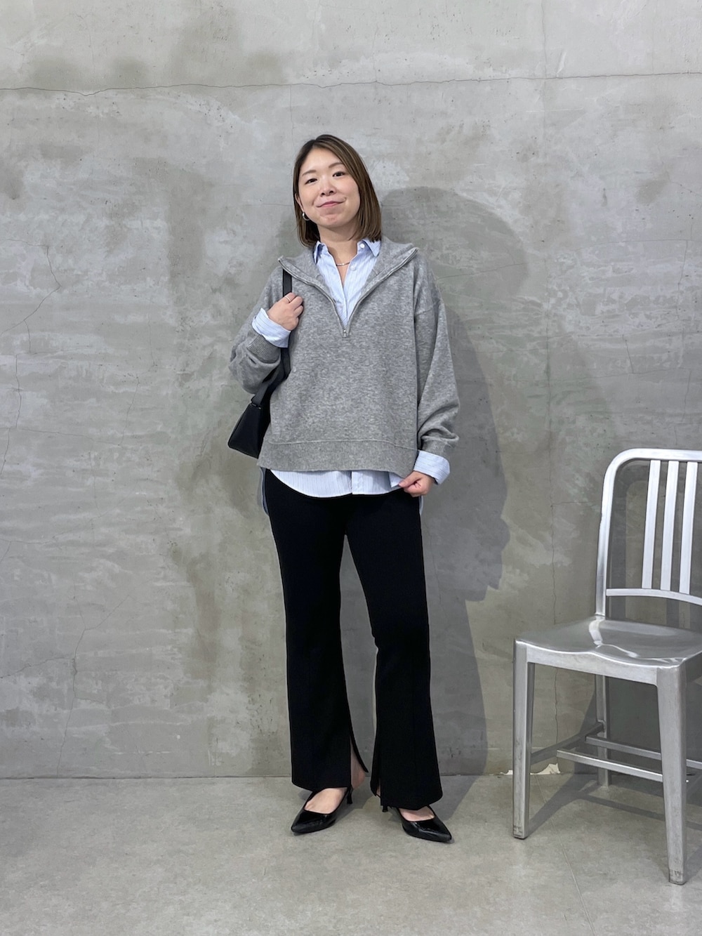 グレー系のニット/セーター、ブルー系のシャツ/ブラウス、ブラック系のスラックスを着用したレディースの秋コーディネートの4枚目の写真