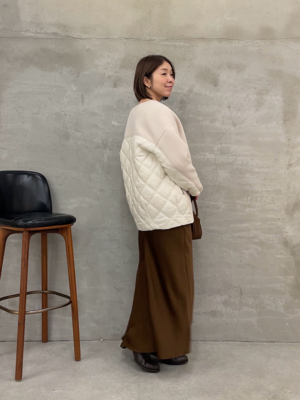 ブラウン系のスカート、ホワイト系のTシャツ/カットソー、ホワイト系のニット/セーターを着用したレディースの秋コーディネートの2枚目の写真