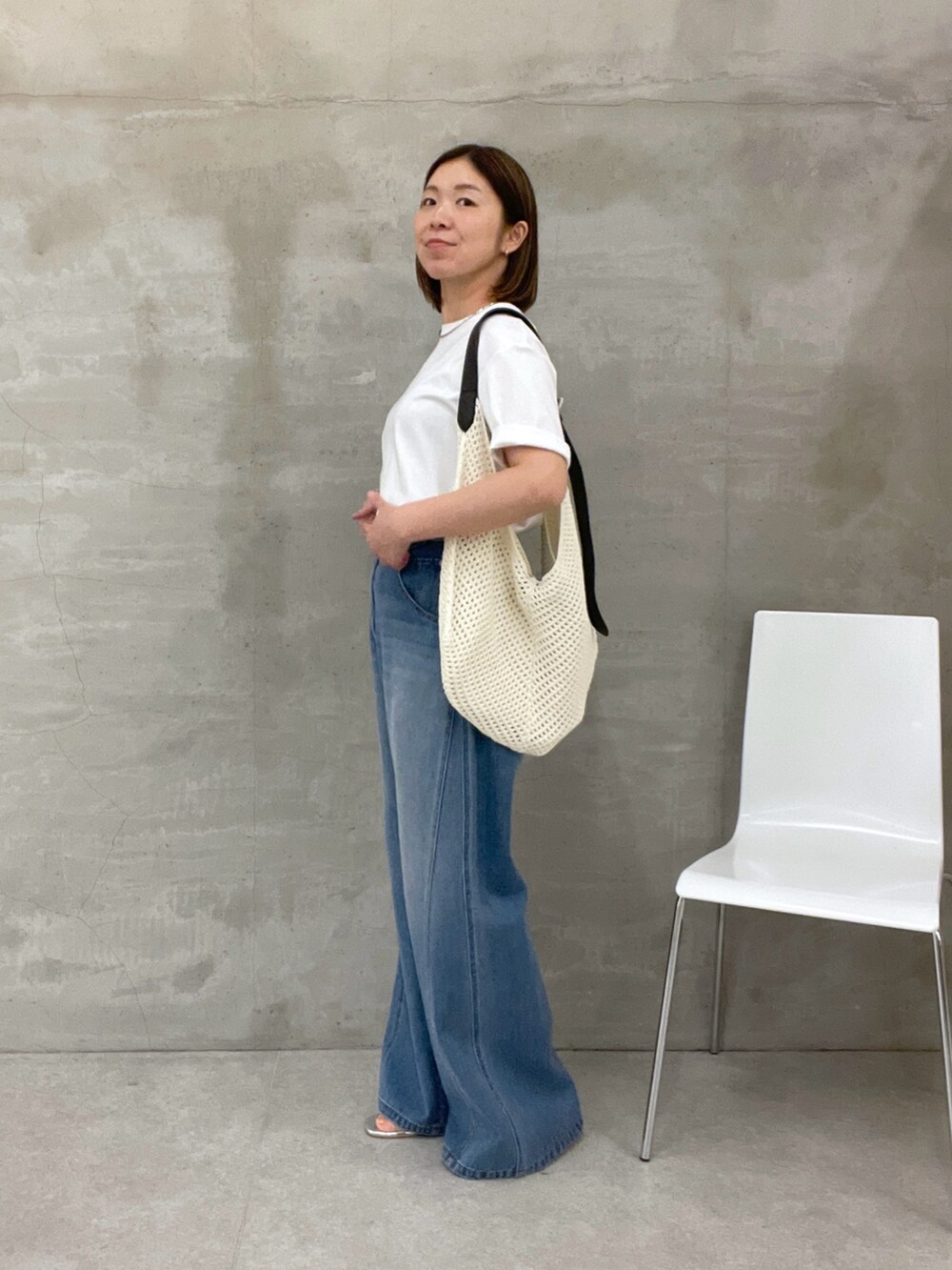 ブルー系のデニムパンツ、ホワイト系のTシャツ/カットソー、ホワイト系のバッグを着用したレディースの夏コーディネートの2枚目の写真