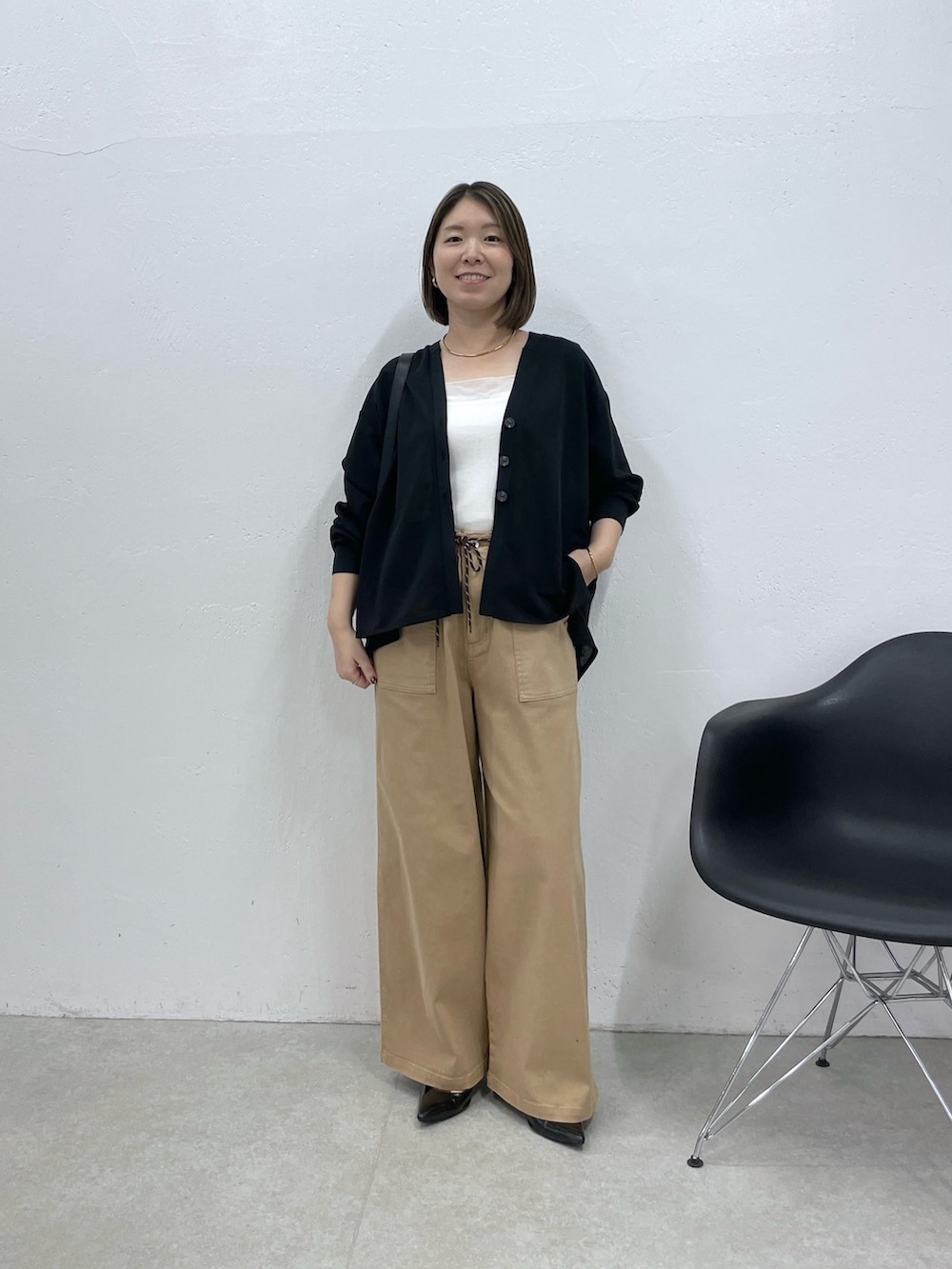 ホワイト系のタンクトップ、ベージュ系のデニムパンツ、ブラック系のカーディガン/ボレロを着用したレディースの夏コーディネートの4枚目の写真