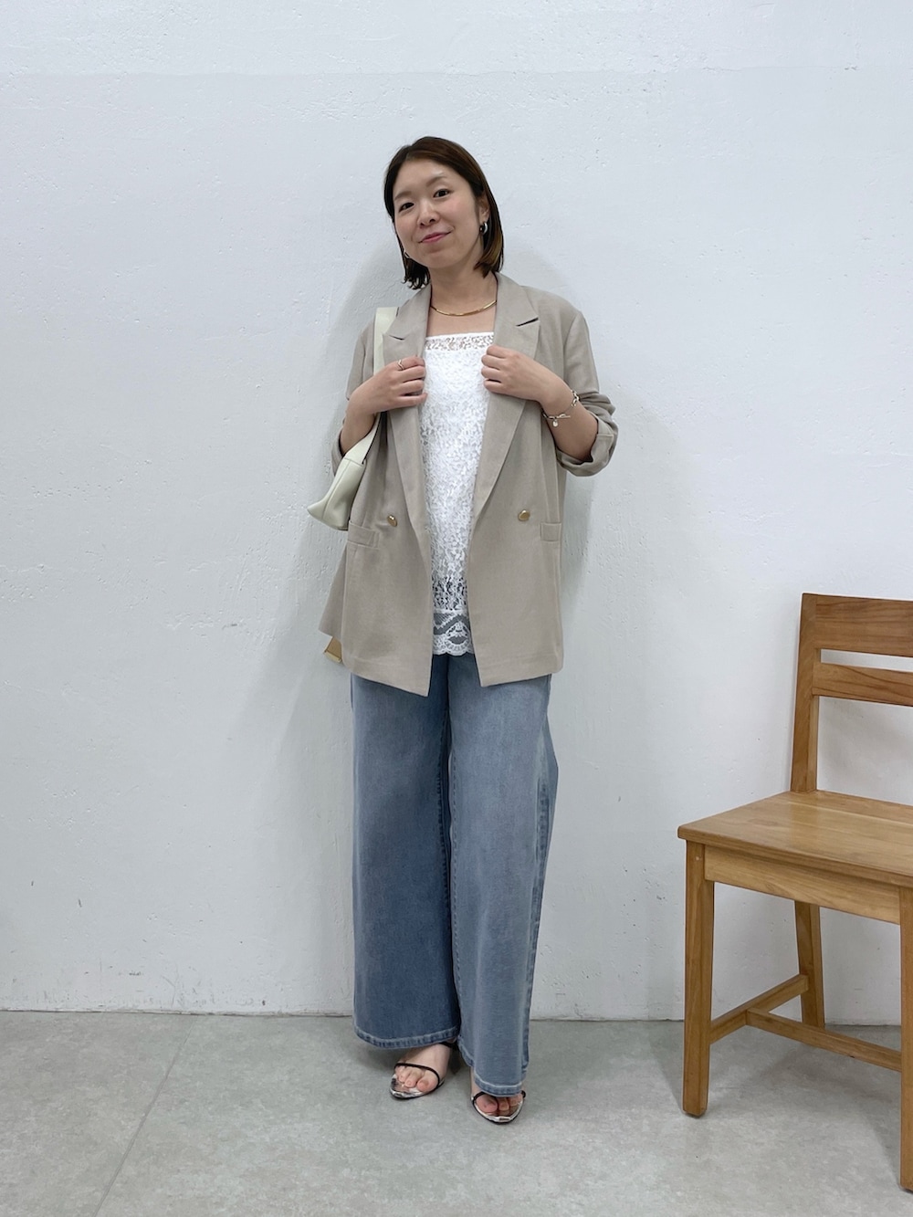 ホワイト系のショルダーバッグ、ベージュ系のテーラードジャケット、ホワイト系のキャミソールを着用したレディースの春コーディネートの5枚目の写真