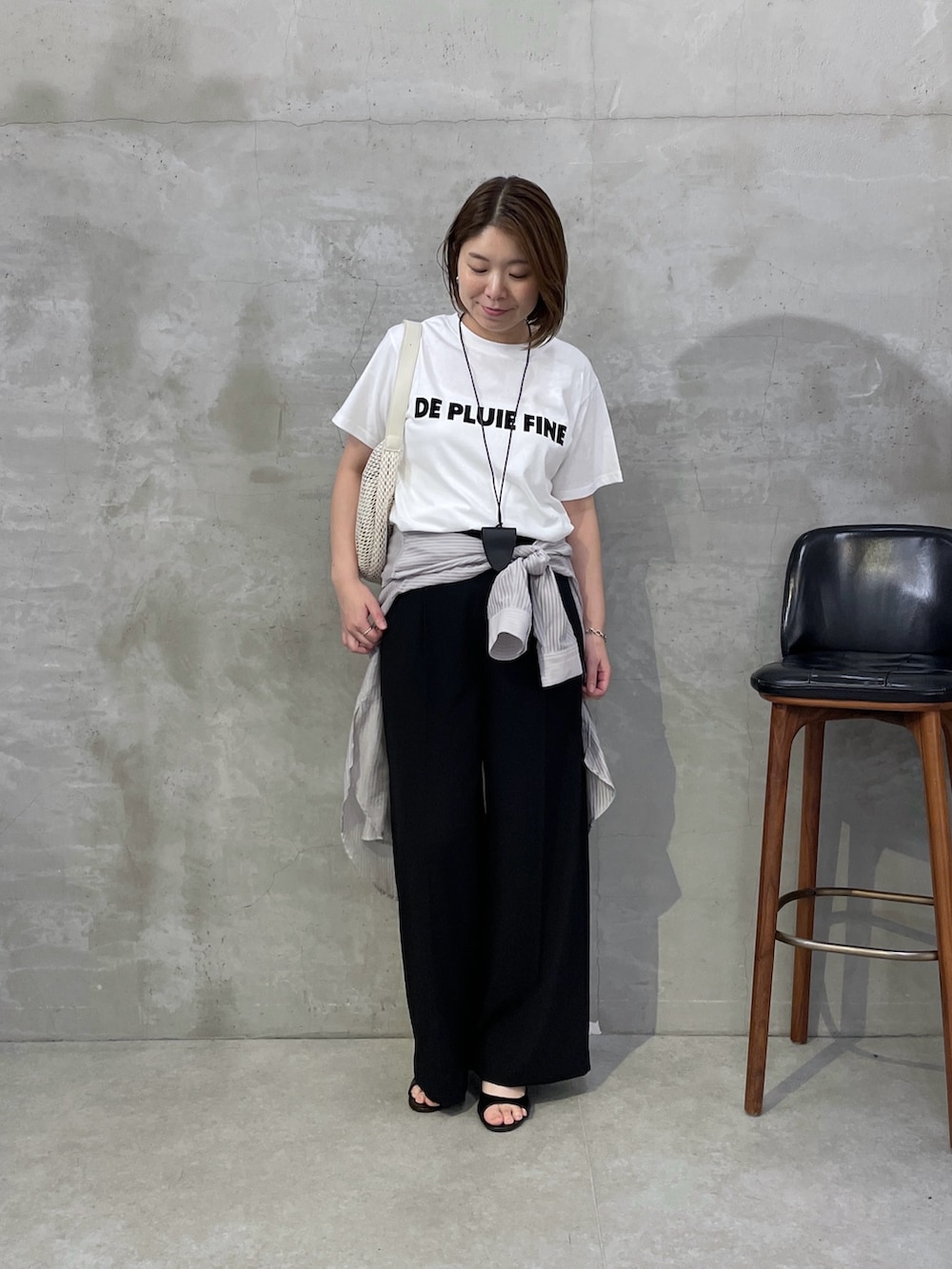 ブラック系のスラックス、ホワイト系のショルダーバッグ、ホワイト系のTシャツ/カットソーを着用したレディースの夏コーディネートの5枚目の写真