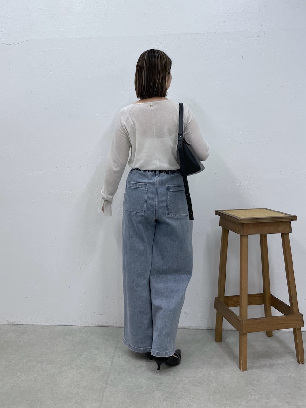 ブルー系のデニムパンツ、ブラック系のショルダーバッグ、ホワイト系のTシャツ/カットソーを着用したレディースの夏コーディネートの2枚目の写真