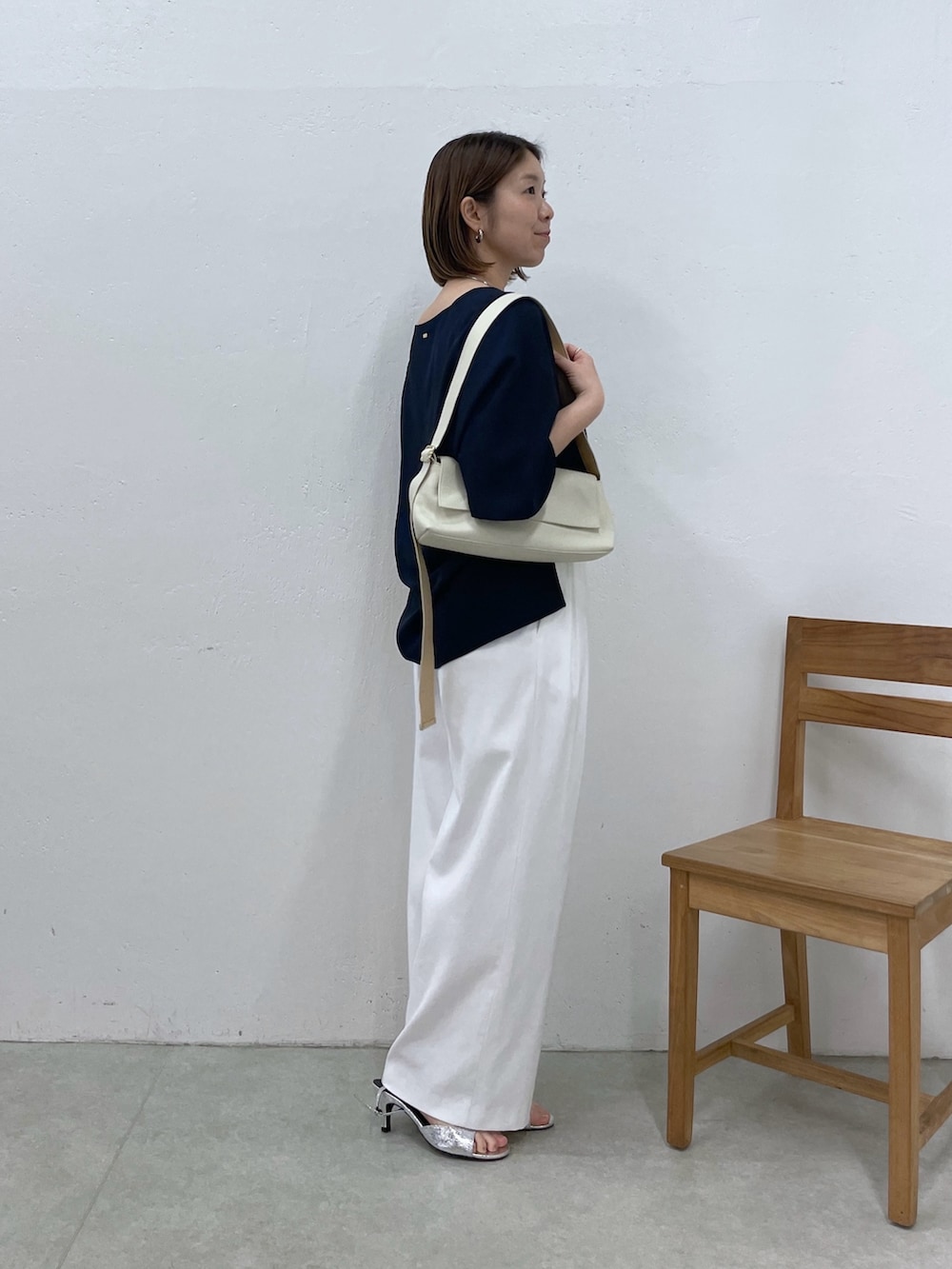 ブルー系のシャツ/ブラウス、ホワイト系のスラックス、ホワイト系のショルダーバッグを着用したレディースの春コーディネートの2枚目の写真