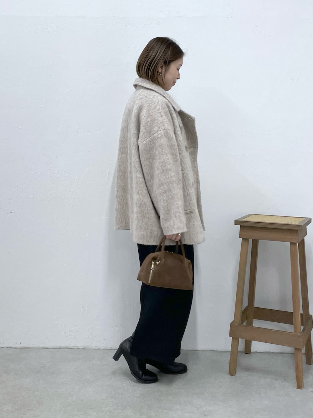 ベージュ系のその他アウター、ブラック系のスカート、ブラウン系のニット/セーターを着用したレディースの冬コーディネートの2枚目の写真