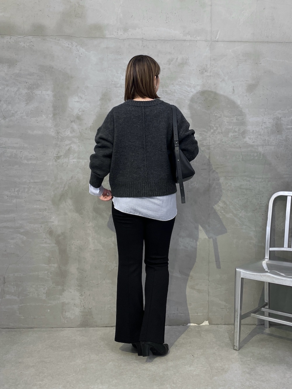 グレー系のニット/セーター、ホワイト系のTシャツ/カットソー、ブラック系のスラックスを着用したレディースの秋コーディネートの3枚目の写真