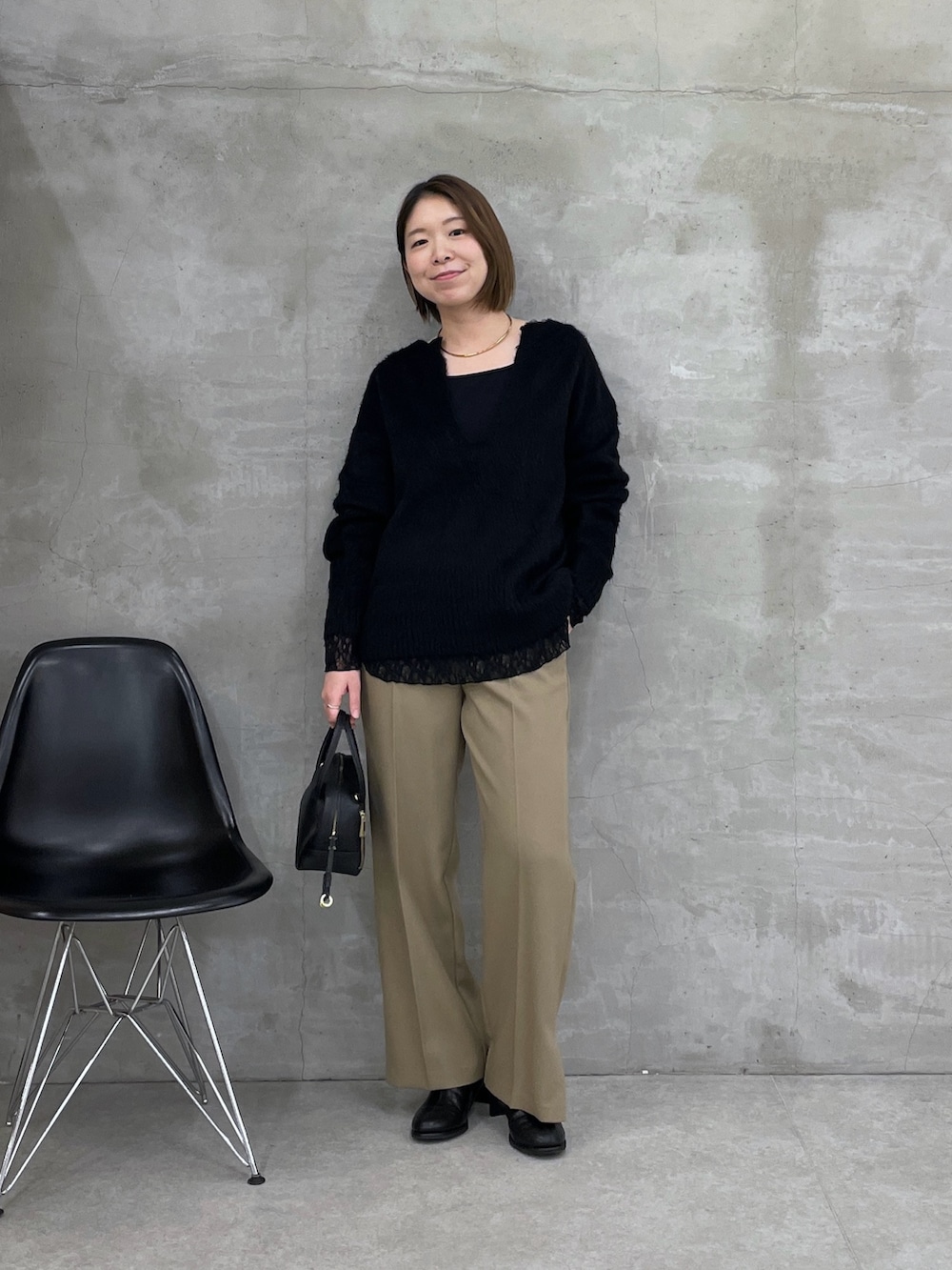 ブラック系のニット/セーター、ブラック系のTシャツ/カットソー、ベージュ系のスラックスを着用したレディースの冬コーディネートの5枚目の写真