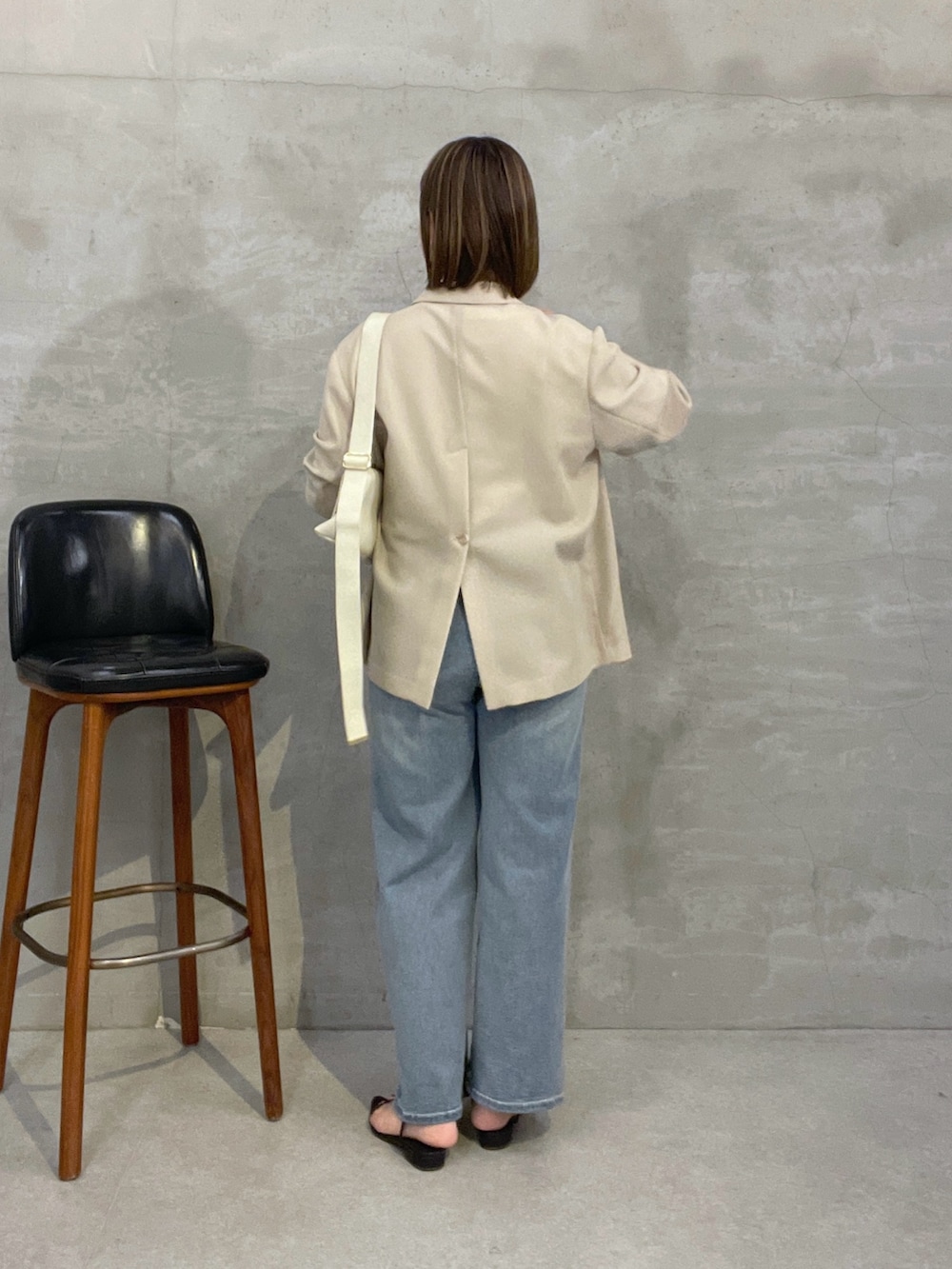 ブルー系のデニムパンツ、ベージュ系のテーラードジャケット、ホワイト系のショルダーバッグを着用したレディースの夏コーディネートの3枚目の写真