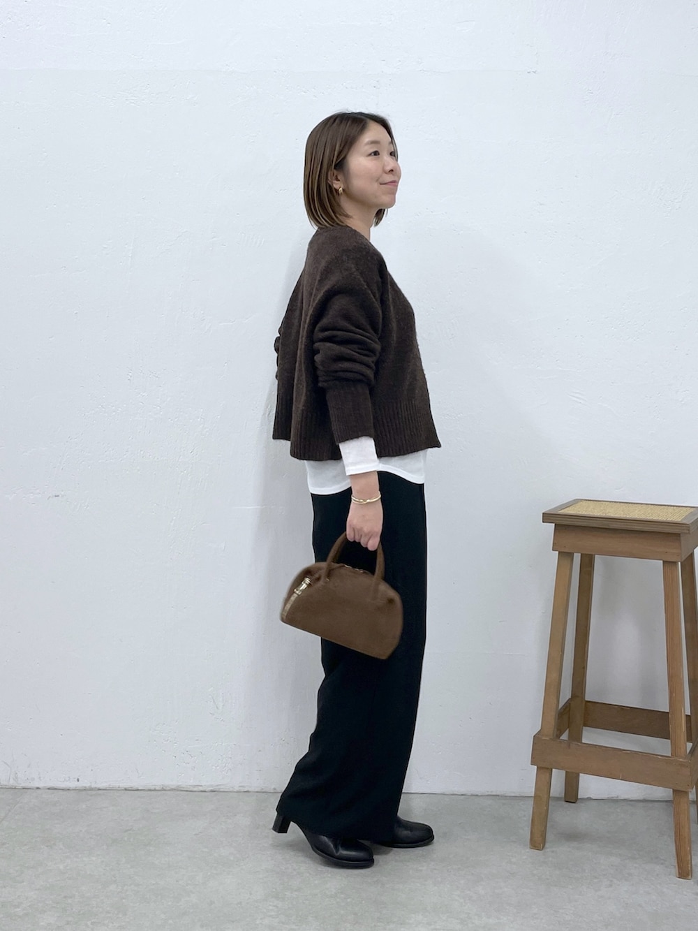 ホワイト系のTシャツ/カットソー、ブラウン系のニット/セーター、ブラック系のスラックスを着用したレディースの冬コーディネートの4枚目の写真