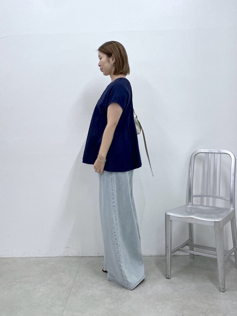ブルー系のTシャツ/カットソー、ブルー系のデニムパンツ、ホワイト系のショルダーバッグを着用したレディースの夏コーディネートの2枚目の写真