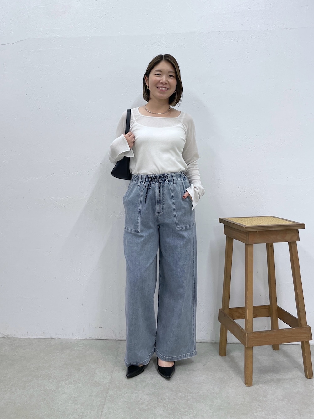 ブルー系のデニムパンツ、ブラック系のショルダーバッグ、ホワイト系のTシャツ/カットソーを着用したレディースの夏コーディネートの4枚目の写真