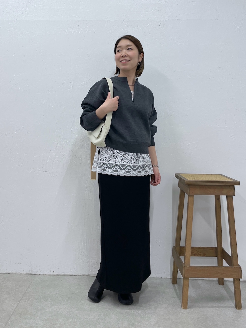 グレー系のニット/セーター、ホワイト系のキャミソール、ブラック系のスカートを着用したレディースの冬コーディネートの5枚目の写真