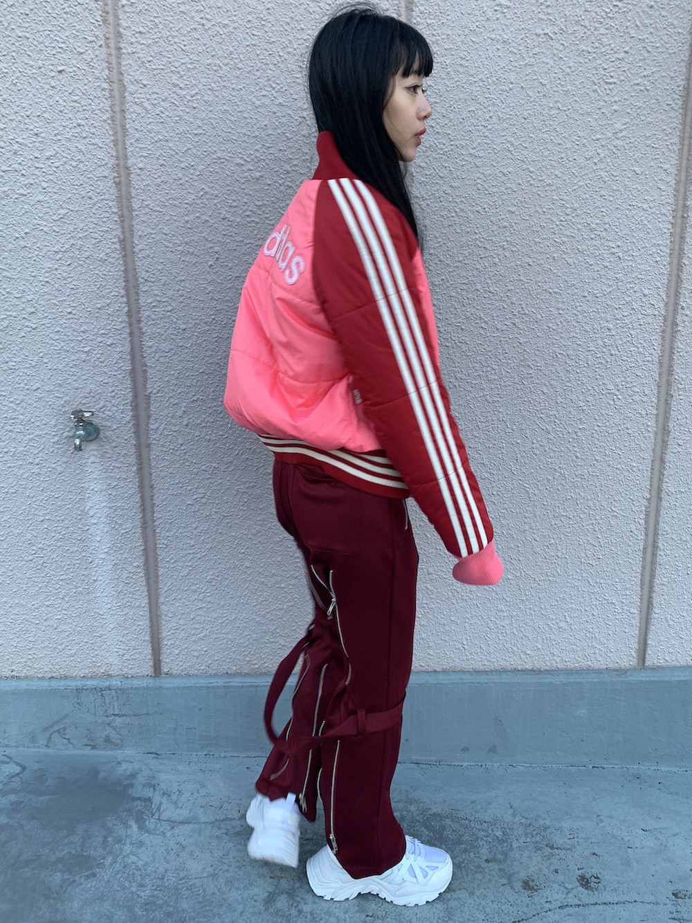 レッド系のジャケット/アウター、レッド系のその他パンツ、ホワイト系のスニーカーを着用したレディースの冬コーディネートの2枚目の写真